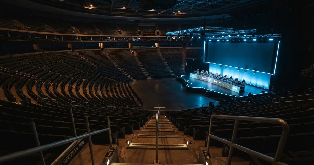 Pusta arena z półkolem siedzisk i oświetloną niebieskim światłem sceną, widok z góry na rzędy foteli.